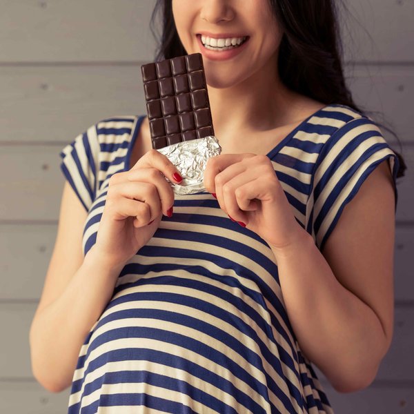 Schwangere Frau mit einer Tafel Schokolade
