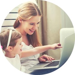 Frau mit Kleinkind, welches mit Finger auf einen Laptop zeigt