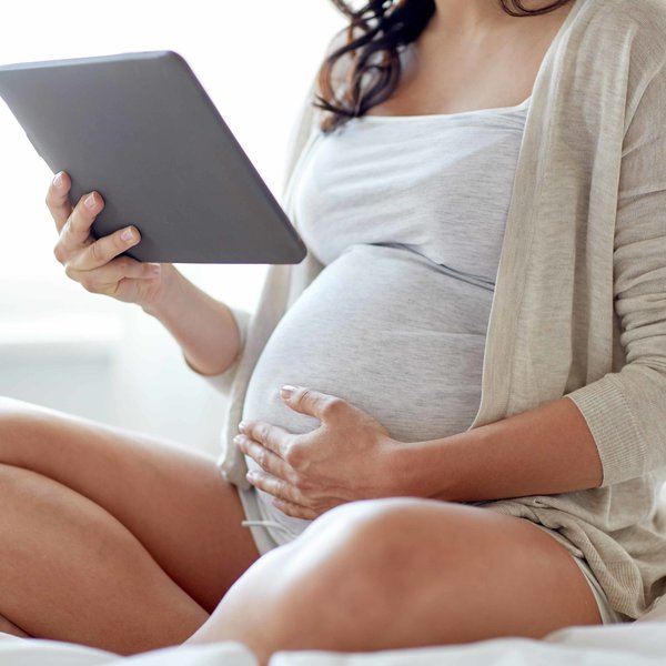 schwangere Frau mit Tablet in der Hand